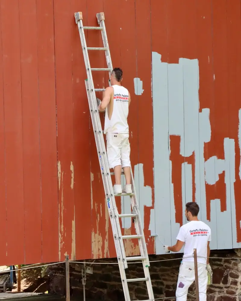 Painting company SEO work: a painter prepping exterior trim on a house