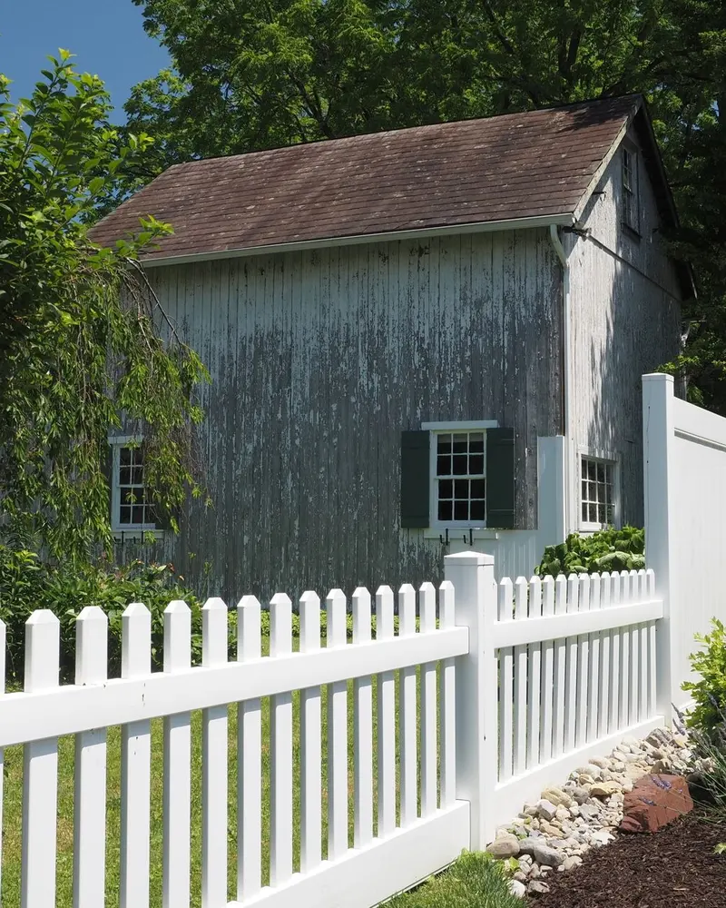 SEO for fence companies: a new white vinyl picket and privacy fence beside a barn